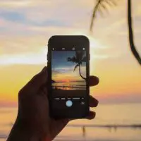 cell phone taking a picture of the sunset on a beach