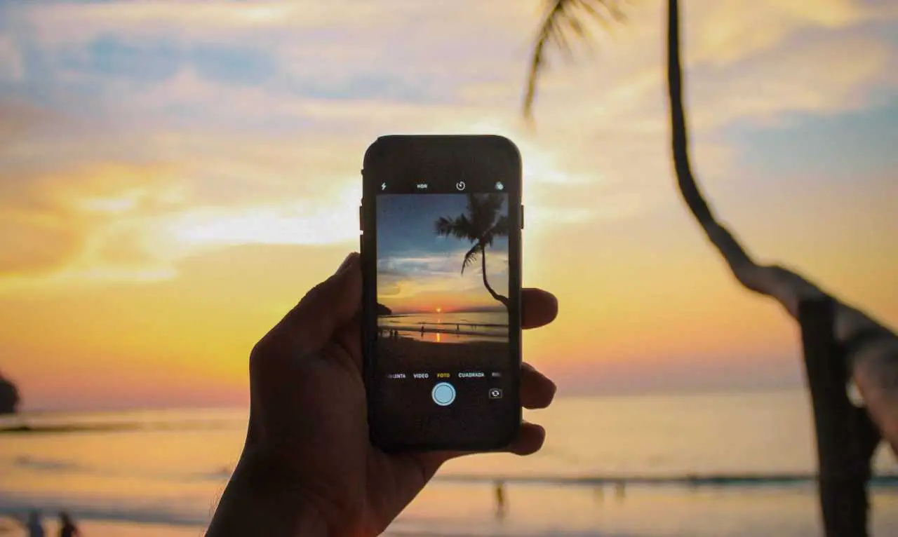 cell phone taking a picture of the sunset on a beach