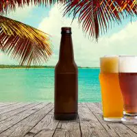 glasses and bottle of beer with beach background